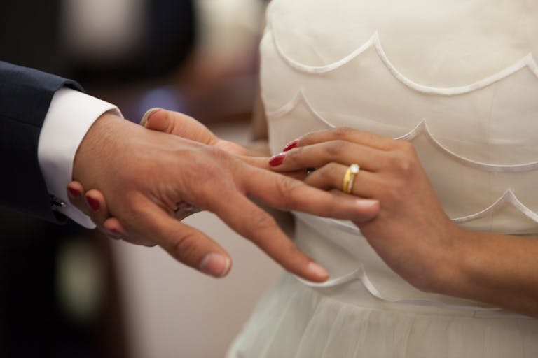Close-up of a bride and groom exchanging rings during their wedding ceremony, symbolizing love and unity.